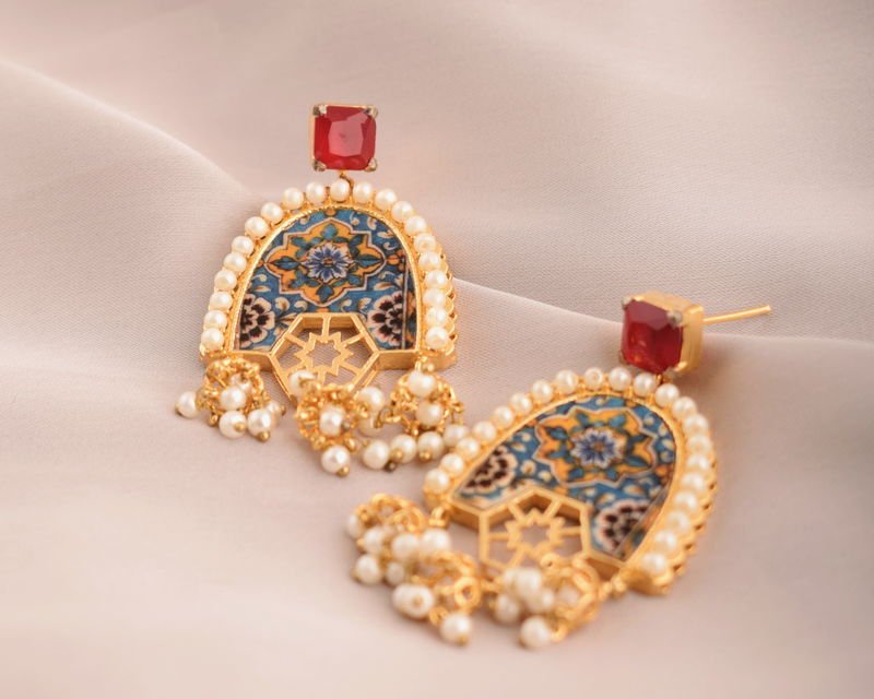 A pair of Arched Arabesque earrings with red zircon tops, blue and ochre painted tile arches, pearl borders and pearl clusters.