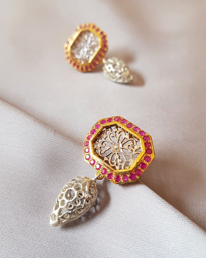 A Jaali filigree earring with an octagonal face outlined in rubies and a pierced silver jhumka drop.