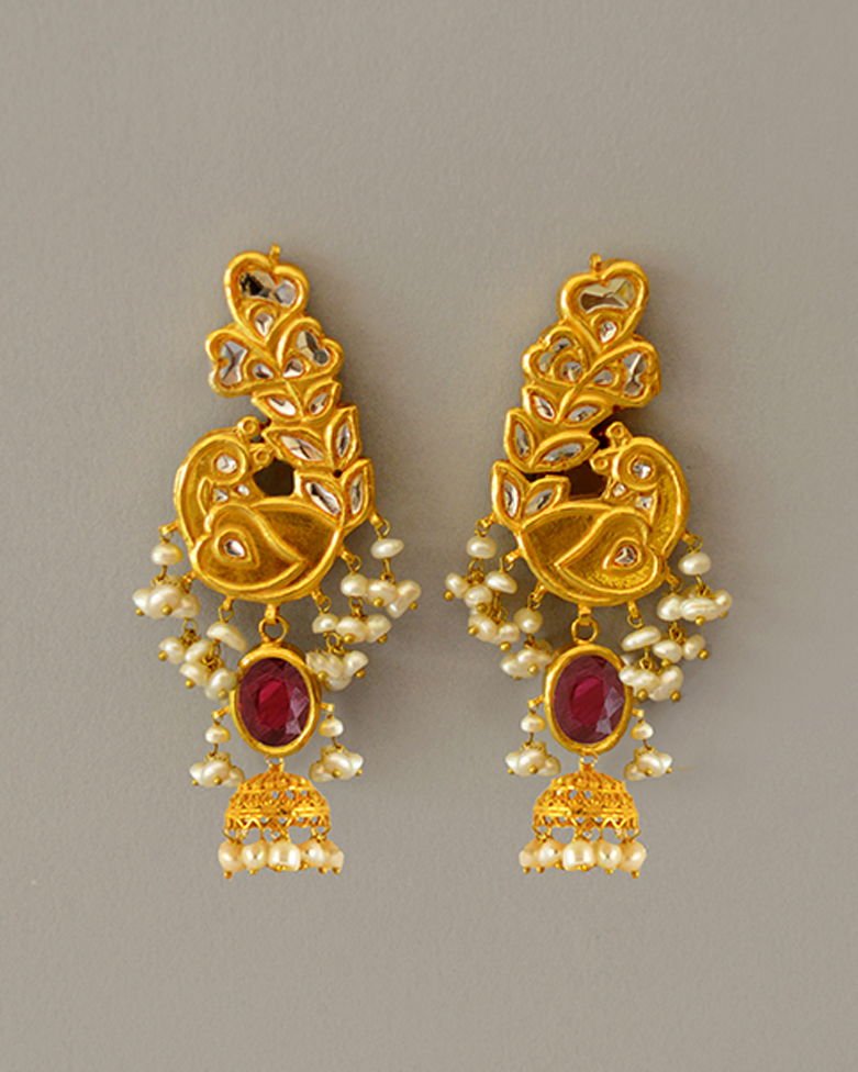 A pair of Mumtaz peacock earrings in kundan with oval ruby cabochons, pearl fringes and jhumka drops.