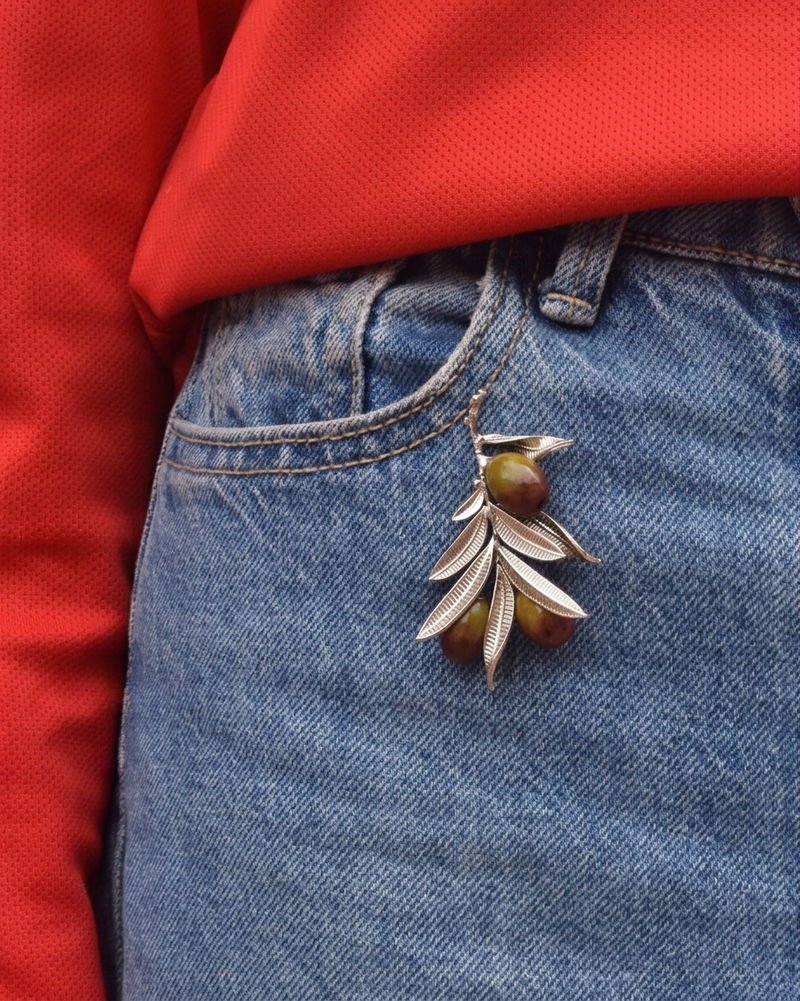 The Olive Branch brooch in silver with hand-painted olives, worn on a printed blue kurta.